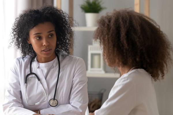 Two Black female doctors speaking to each other