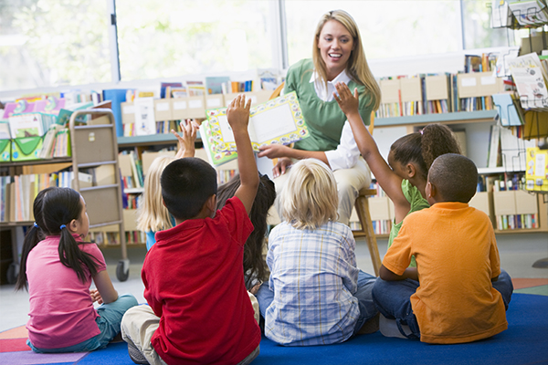 Kids in a classroom reading a book with their teacher.