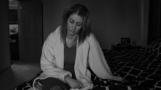 Woman sitting on bed looking distraught