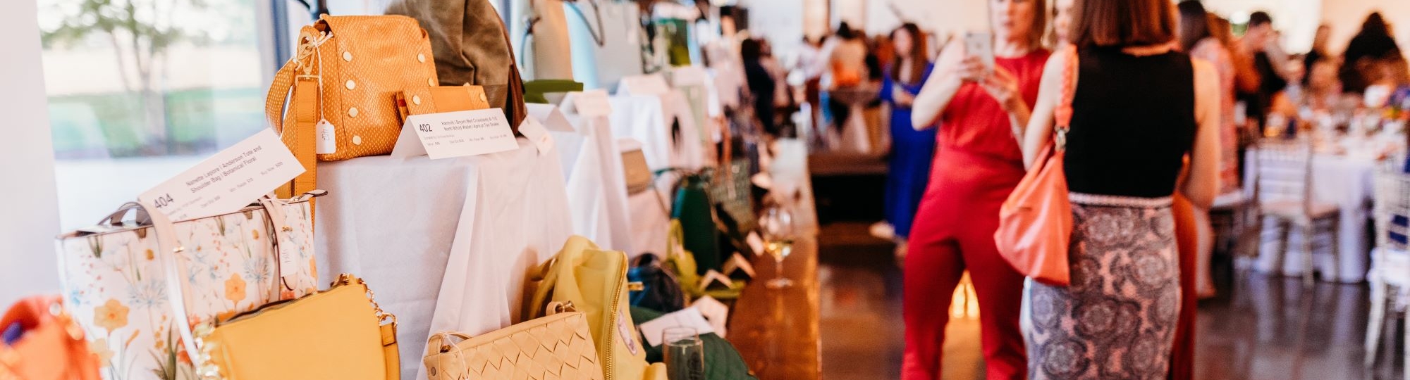 Women browsing silent auction purses