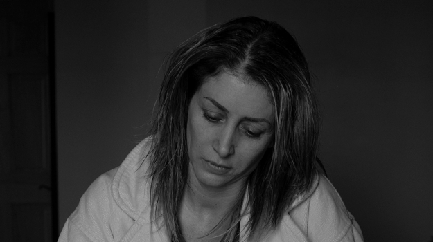 Woman sitting on bed looking distraught