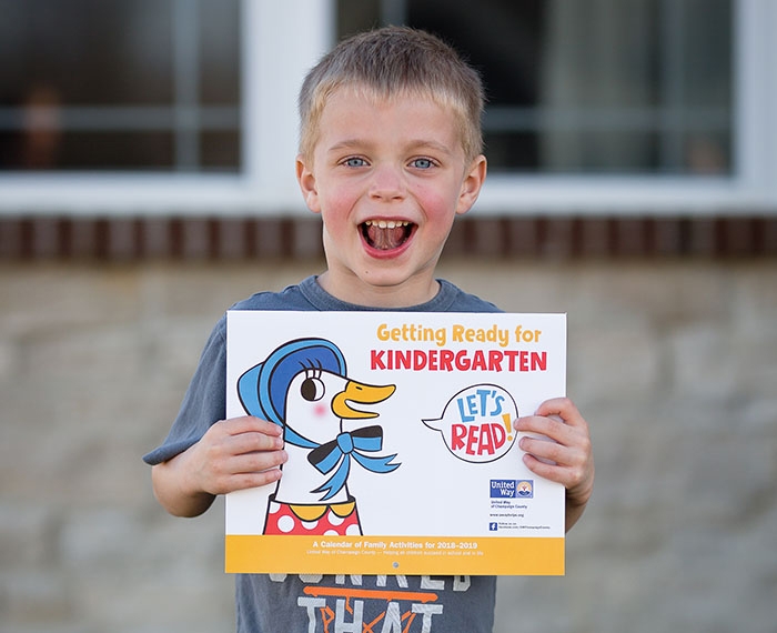 smiling boy holding up a book